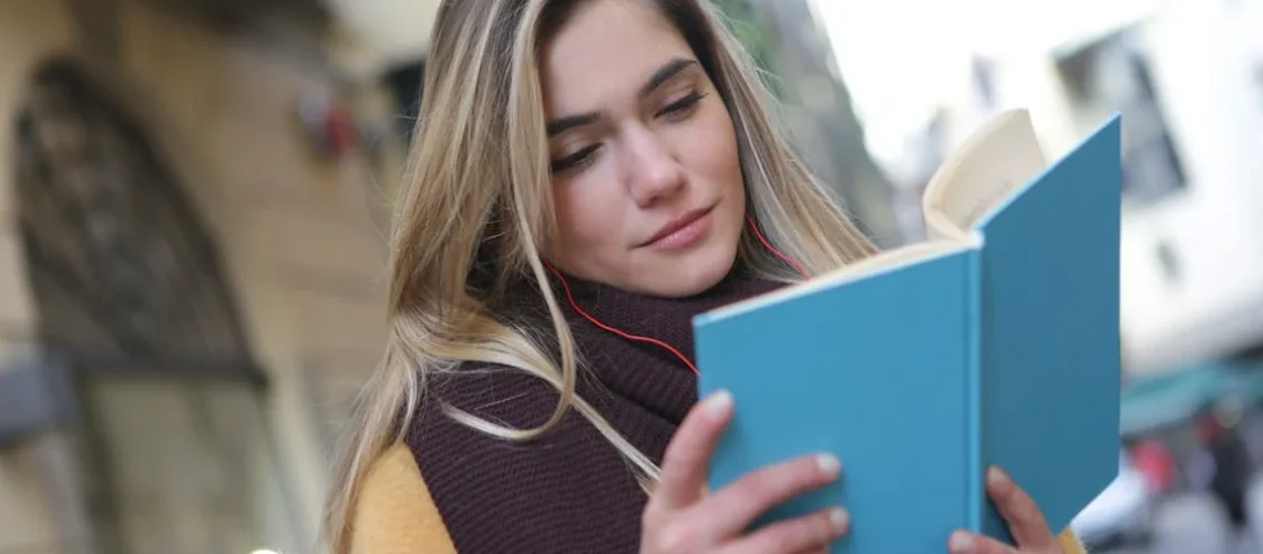 Ung kvinna / ungdom läser en bok utomhus, funderar över sabbatsår efter gymnasiet.